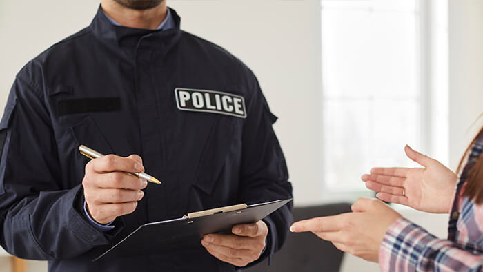 Police officer in uniform writing down testimonies while interviewing witness