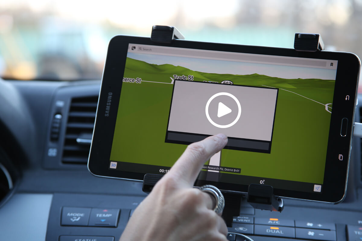 A hand extended to touch the play button of an infotainment system inside of a vehicle.