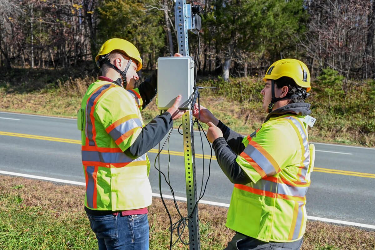 Virginia Tech Transportation Institute researchers (from left) Will Vaughn and Daniel Burdisso install part of the VTTI Smart Work Zone on a road sign. Photo by Jean Paul Talledo Vilela.