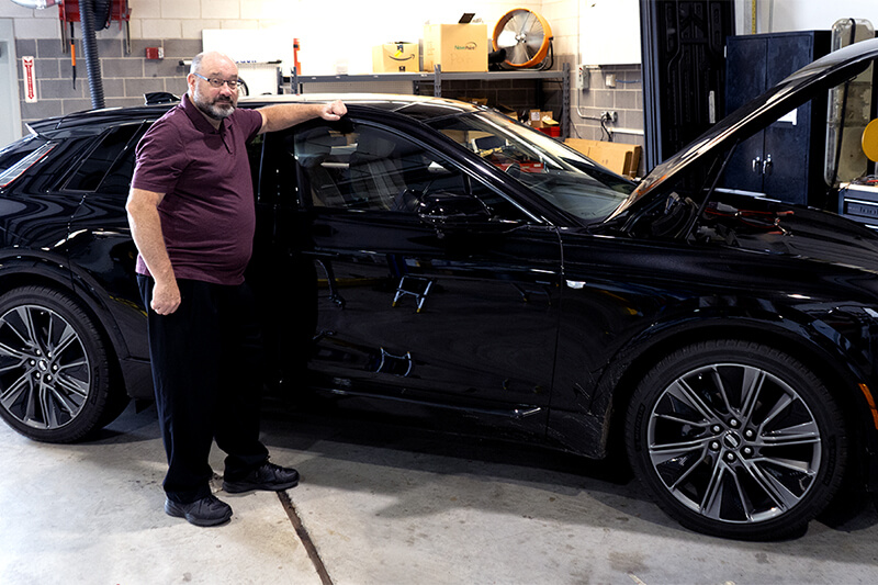 Photo of Jonathan Hankey standing in front of a black car in a garage