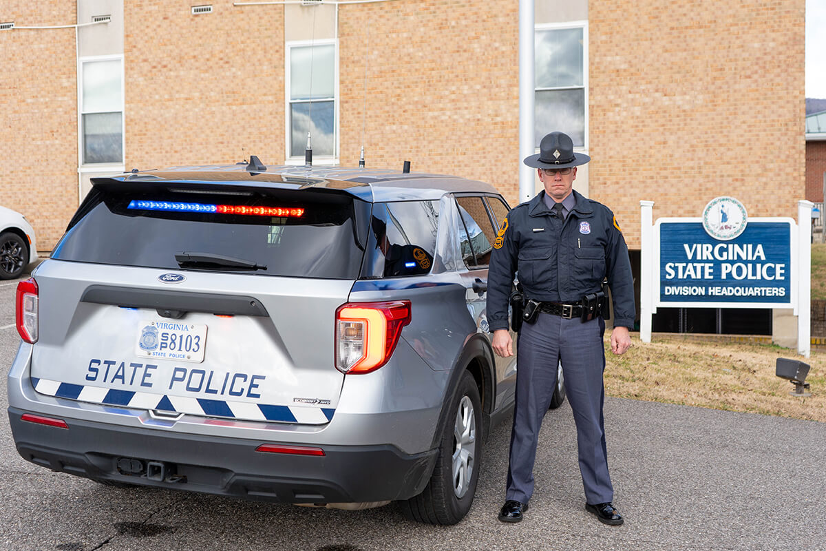 Virginia State Police trooper standing next to a new patrol vehicle with red and blue lights at the Salem District 6 Virginia State Police headquarters.