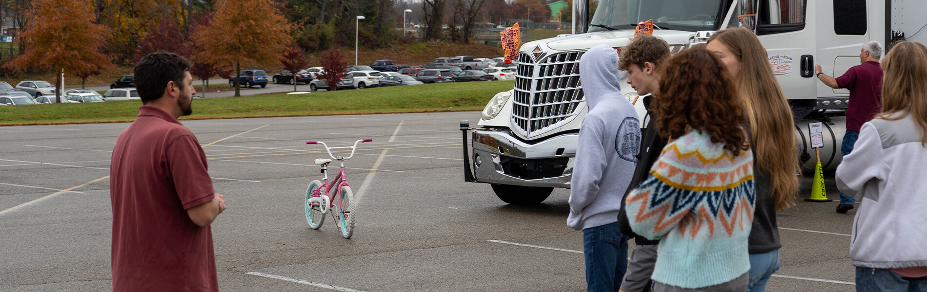 Person teaching teenagers in front of a tractor trailer